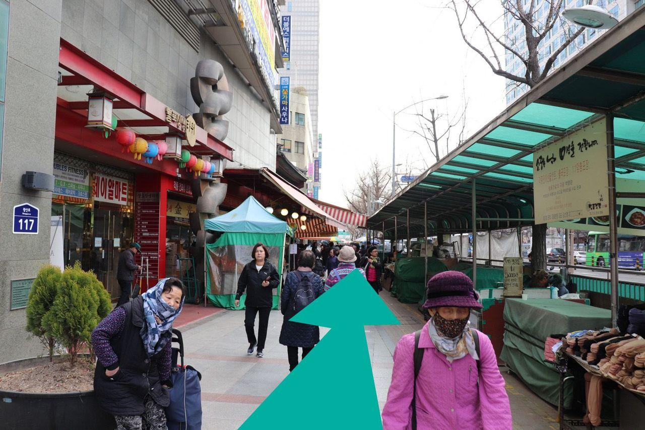 Con đường dẫn đến chợ nhân sâm, có bảng chỉ dẫn bên cạnh và nhiều người đi bộ.